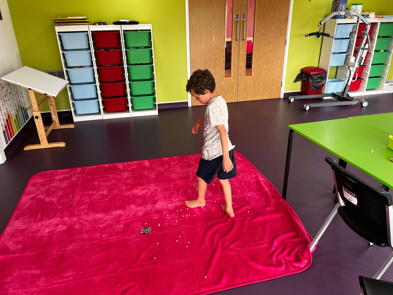 Child engaged in sensory motor play on a mat in the activity room